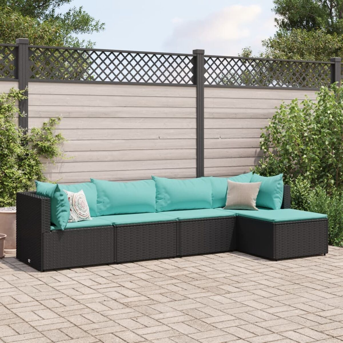 Divano componibile in vimini nero con cuscini turchese su un patio.