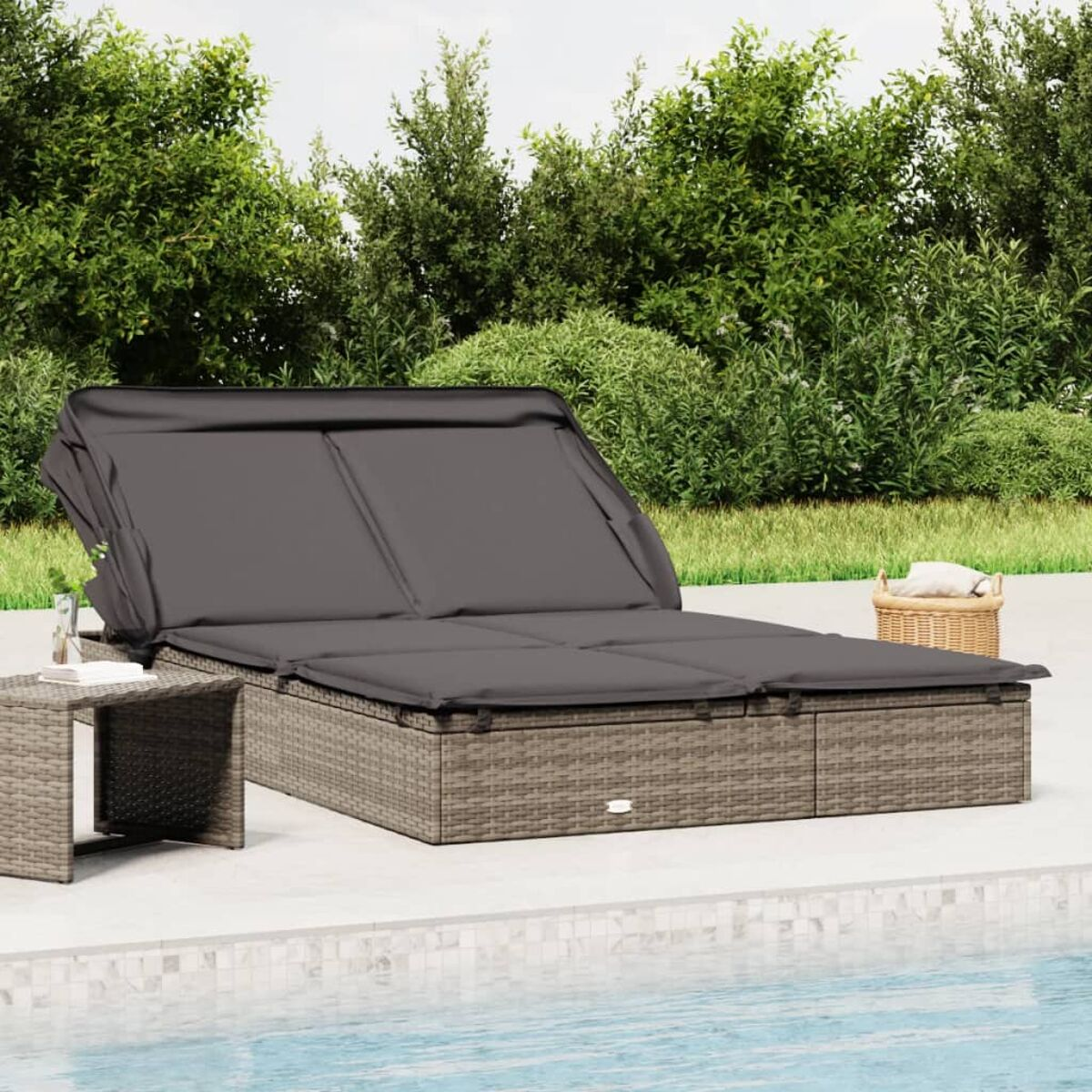 Ein graues Korbliegenbett mit dunkelgrauem Baldachin und Kissen am Pool.
