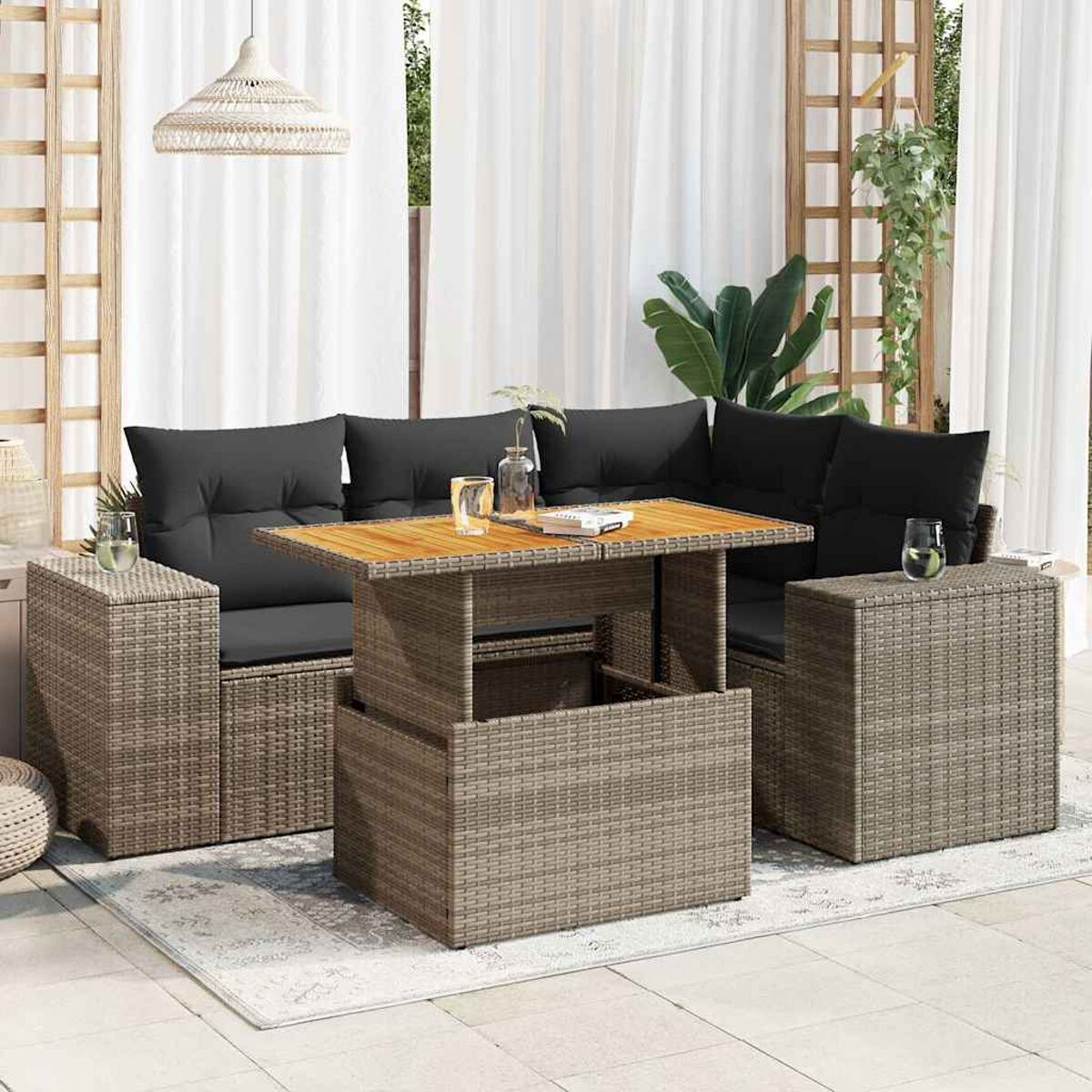 Set divano in rattan da esterno con tavolo sollevabile e due tavolini, su un patio bianco.