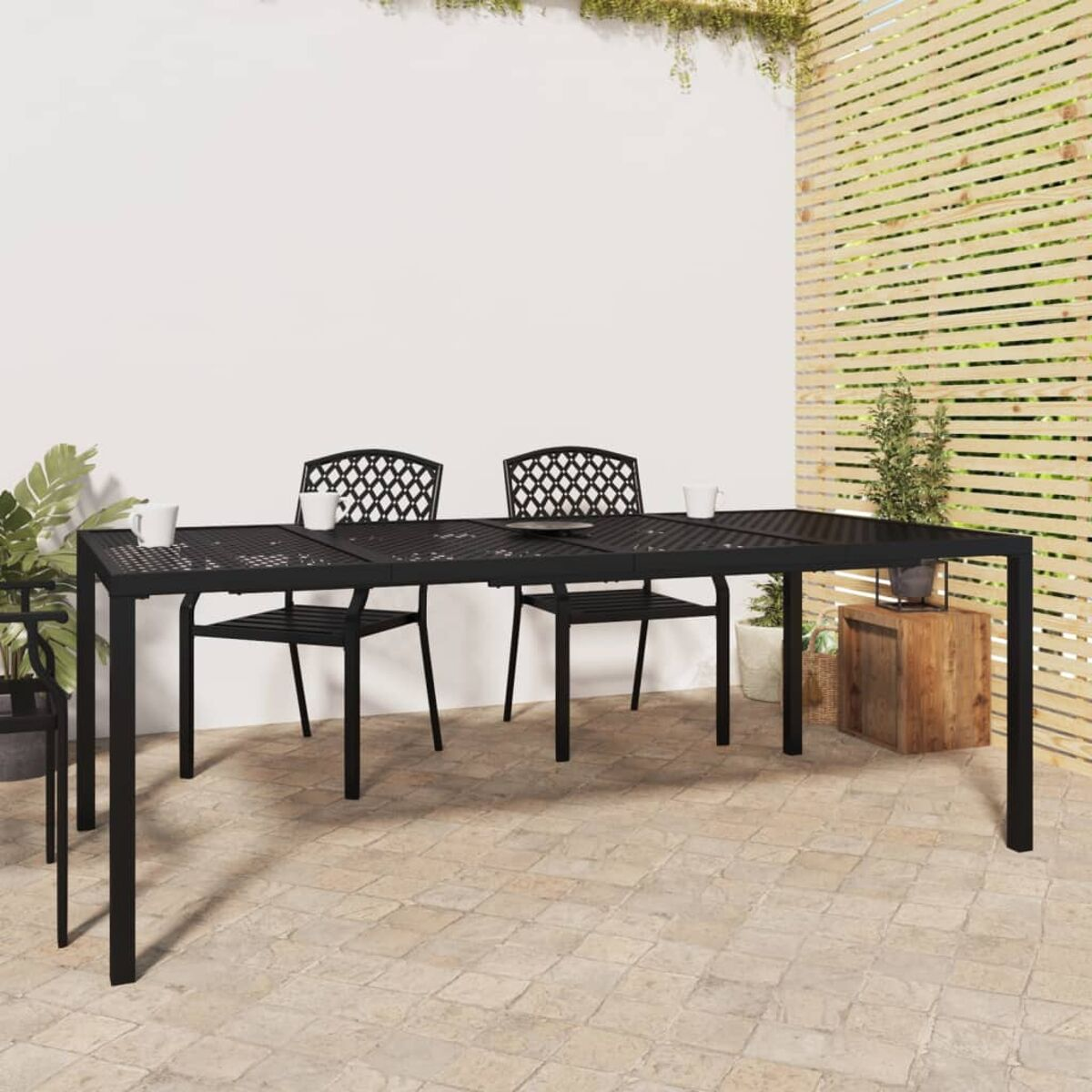 Gartengarnitur mit schwarzem Metalltisch und Stühlen. Auf Steinplatten-Terrasse.