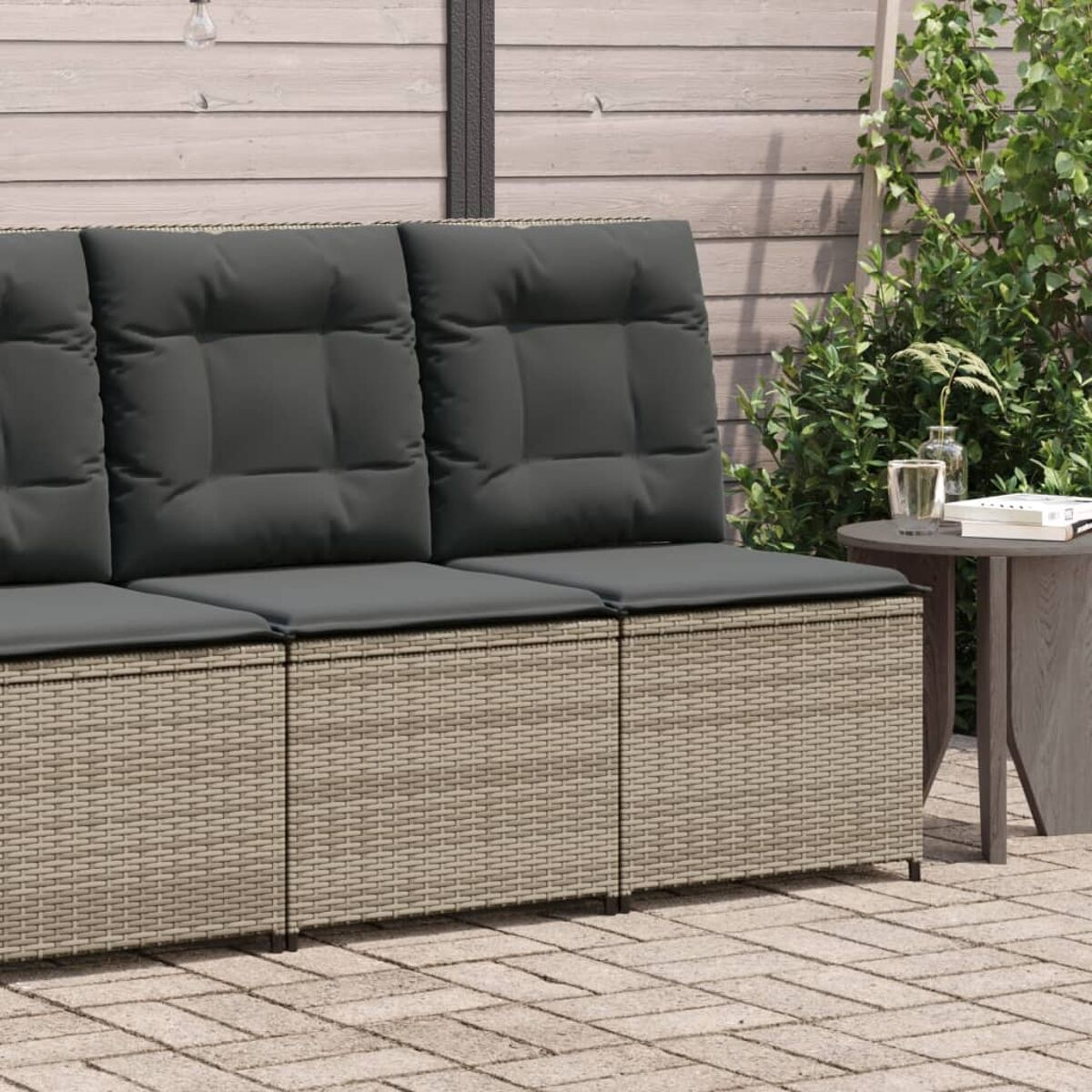 Ein graues Outdoor-Sofa mit drei Sitzkissen. Der Hintergrund ist ein Holzzaun.