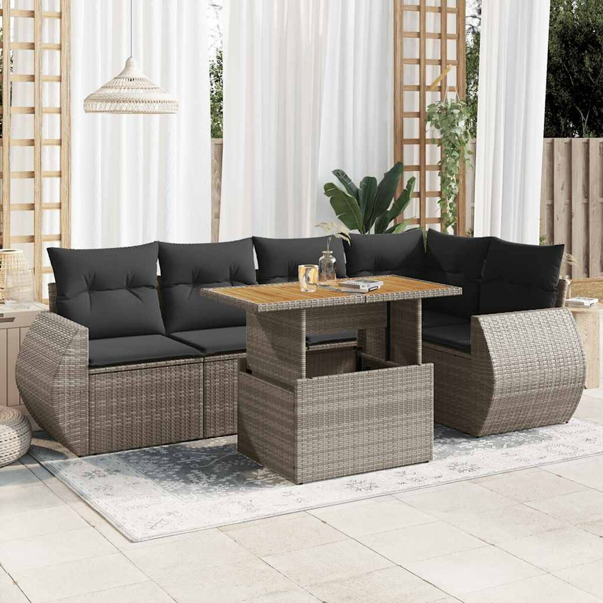 Gartenmöbel-Set mit grauen Kissen, Holztisch und weißen Vorhängen im Hintergrund.