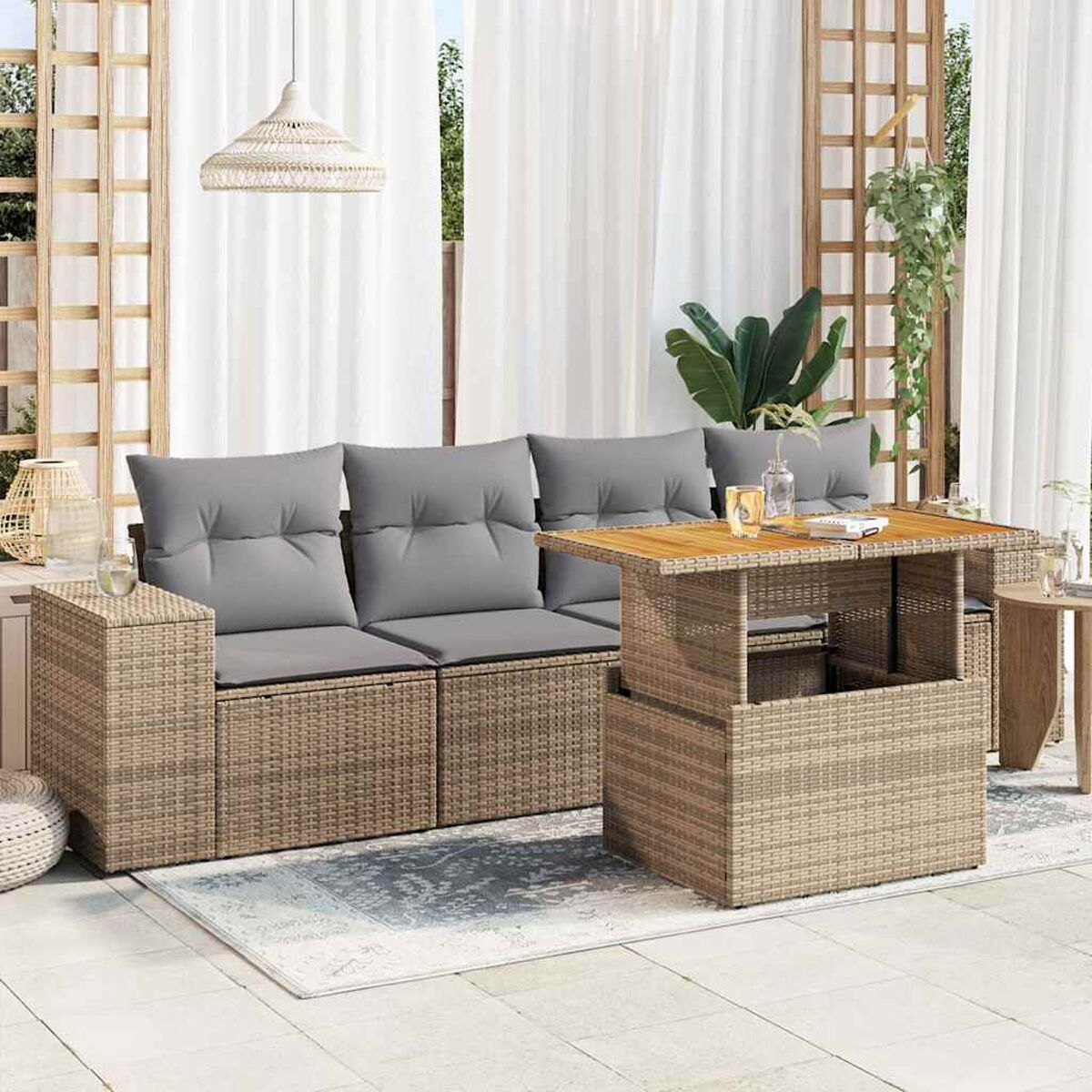 Escena de patio con sofá de mimbre beige, mesa y decoración. Cortinas blancas al fondo.