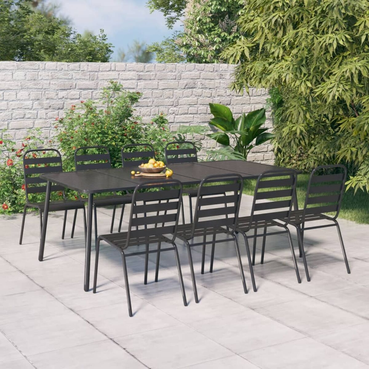 Schwarzes Ess-Set für draußen mit Tisch und sechs Stühlen auf einer Terrasse. Hintergrund ist eine Ziegelmauer und Grün.