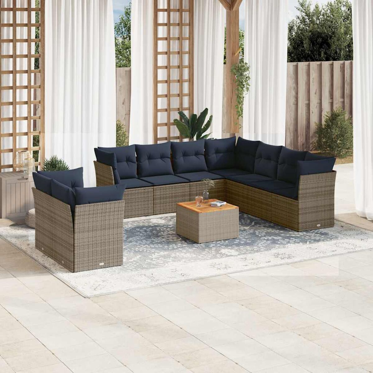 Set di mobili da esterno in vimini con cuscini blu navy, un tavolino quadrato e un tappeto fantasia.