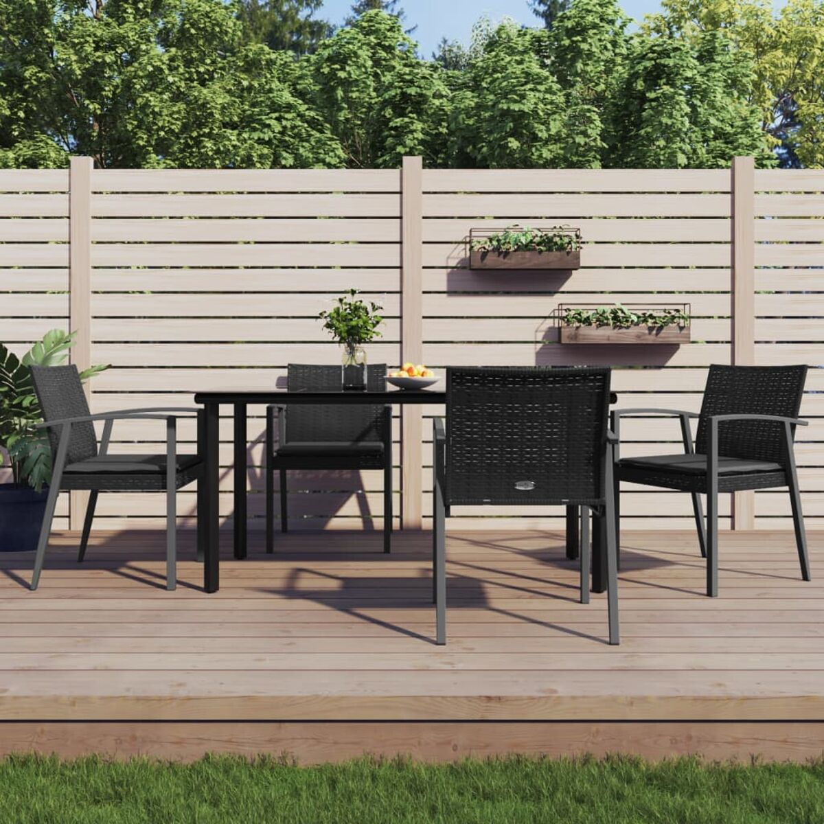 Essgruppe für den Außenbereich mit schwarzen Stühlen und Tisch auf Holzterrasse. Rasen.