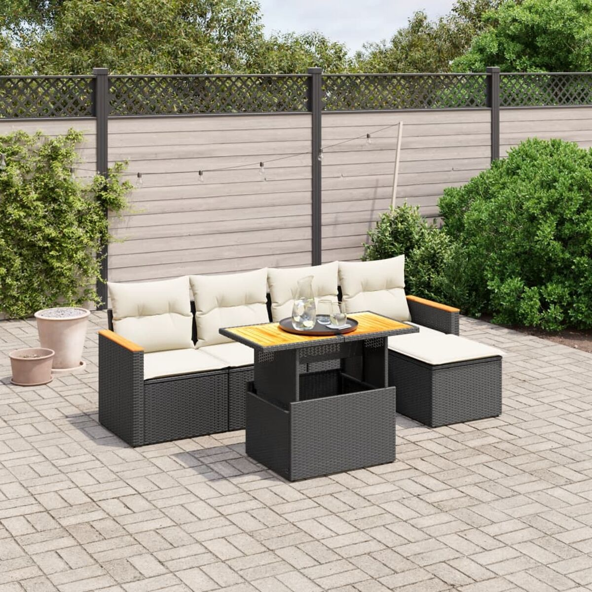 Outdoor-Sofa-Set aus schwarzem Korbgeflecht mit cremefarbenen Kissen, Tisch mit Hebetischplatte.