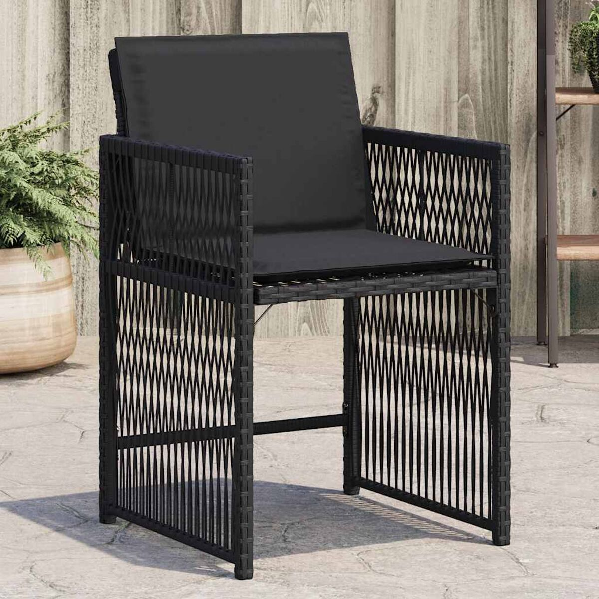 Sedia in rattan nero con cuscino nero, all'aperto.