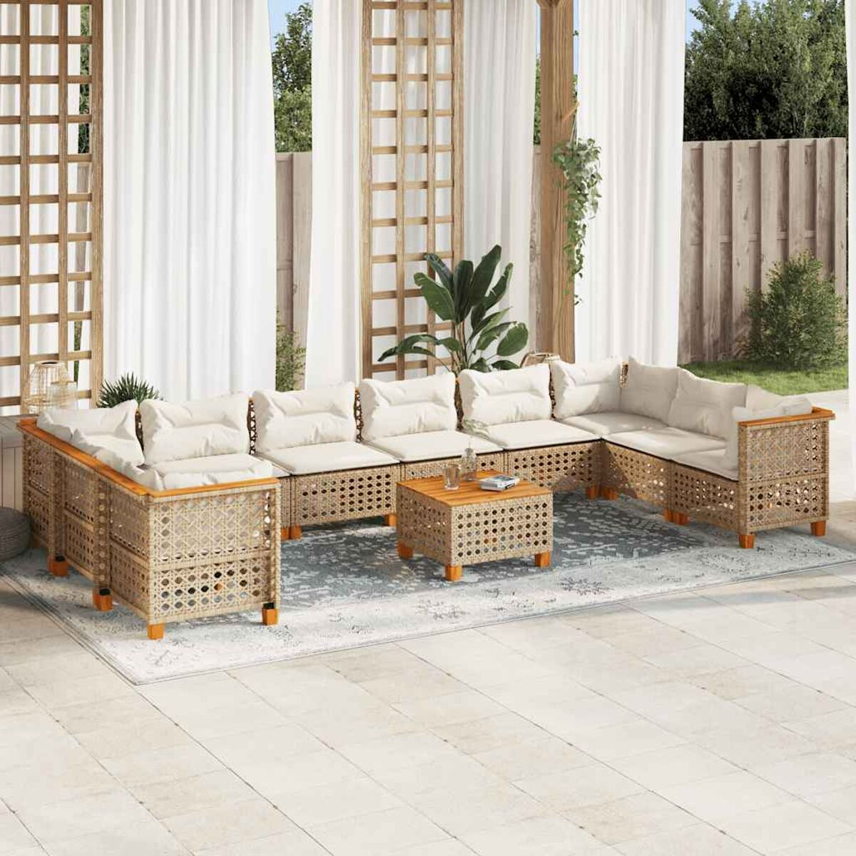 Set di mobili in rattan da esterno con cuscini bianchi, su un patio con tende bianche.