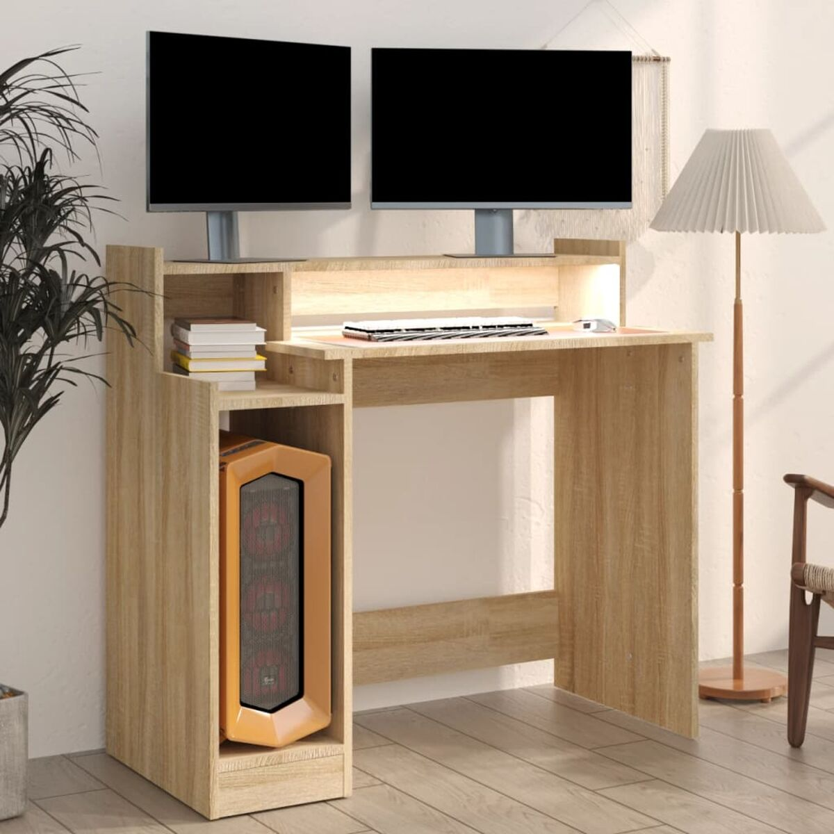 Ein Computertisch mit zwei Monitoren, einem PC-Tower und einer Lampe. Der Schreibtisch ist hellbraun.