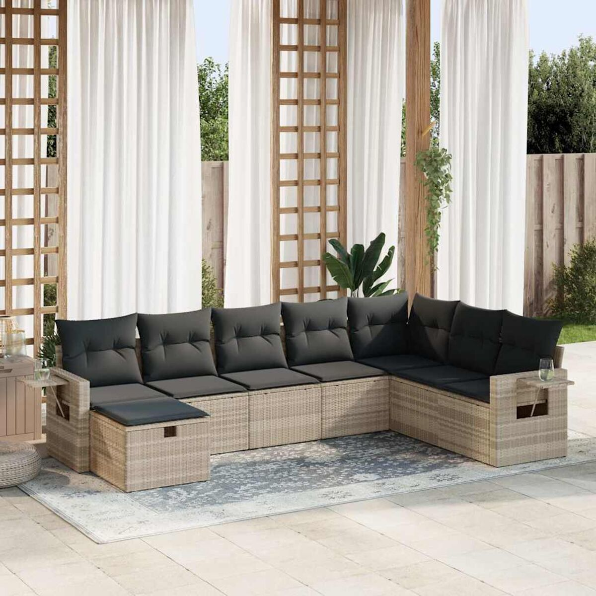L-förmiges Outdoor-Sofa mit Kissen, einem Beistelltisch und einem Teppich. Vorhänge und Pflanzen im Hintergrund.