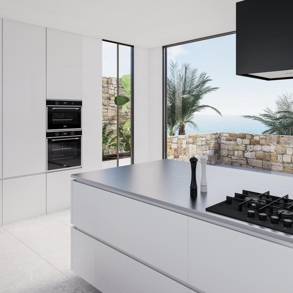 Cucina moderna con isola. Mobili bianchi, elettrodomestici neri e vista mare.