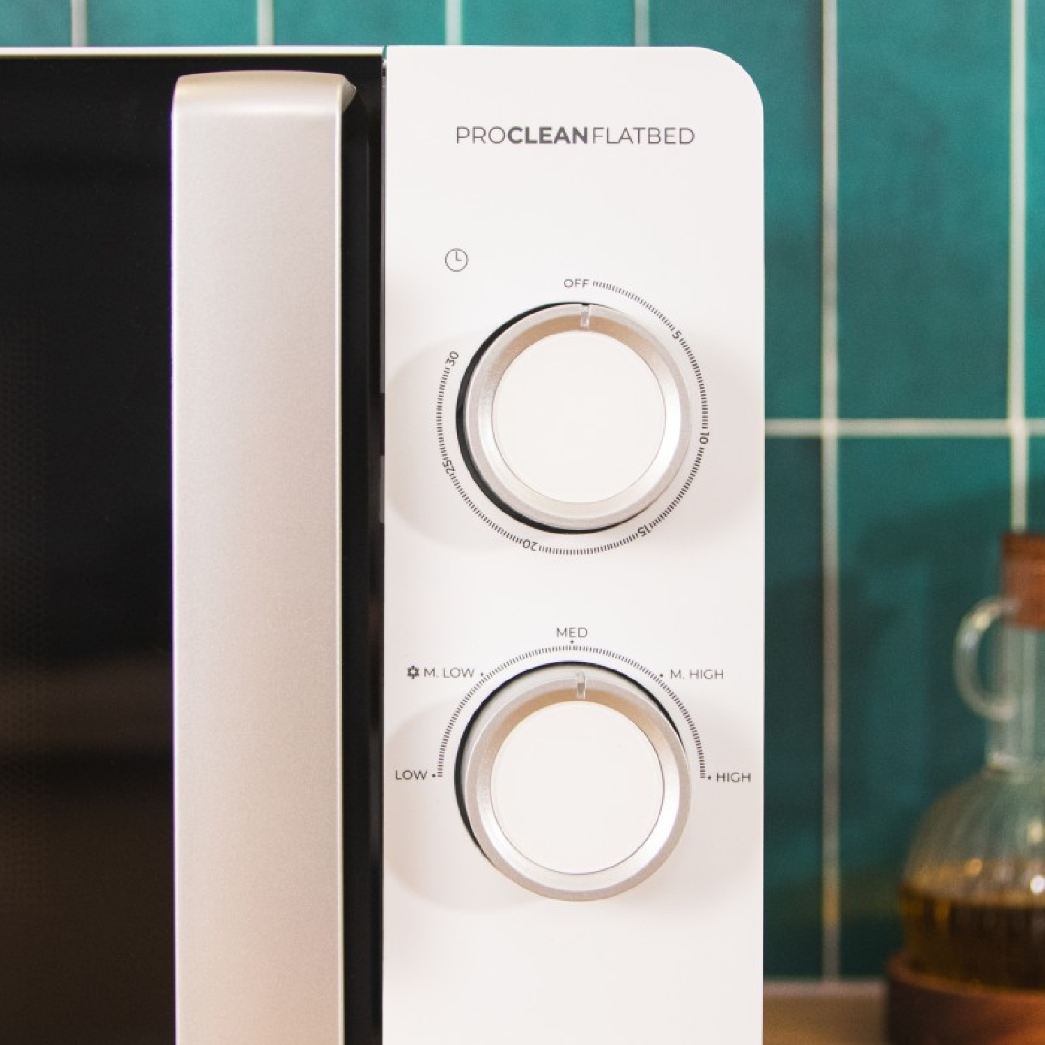 Zbliżenie panelu sterowania kuchenki mikrofalowej. Biały z pokrętłami i przyciskami. Czas to 12:30.