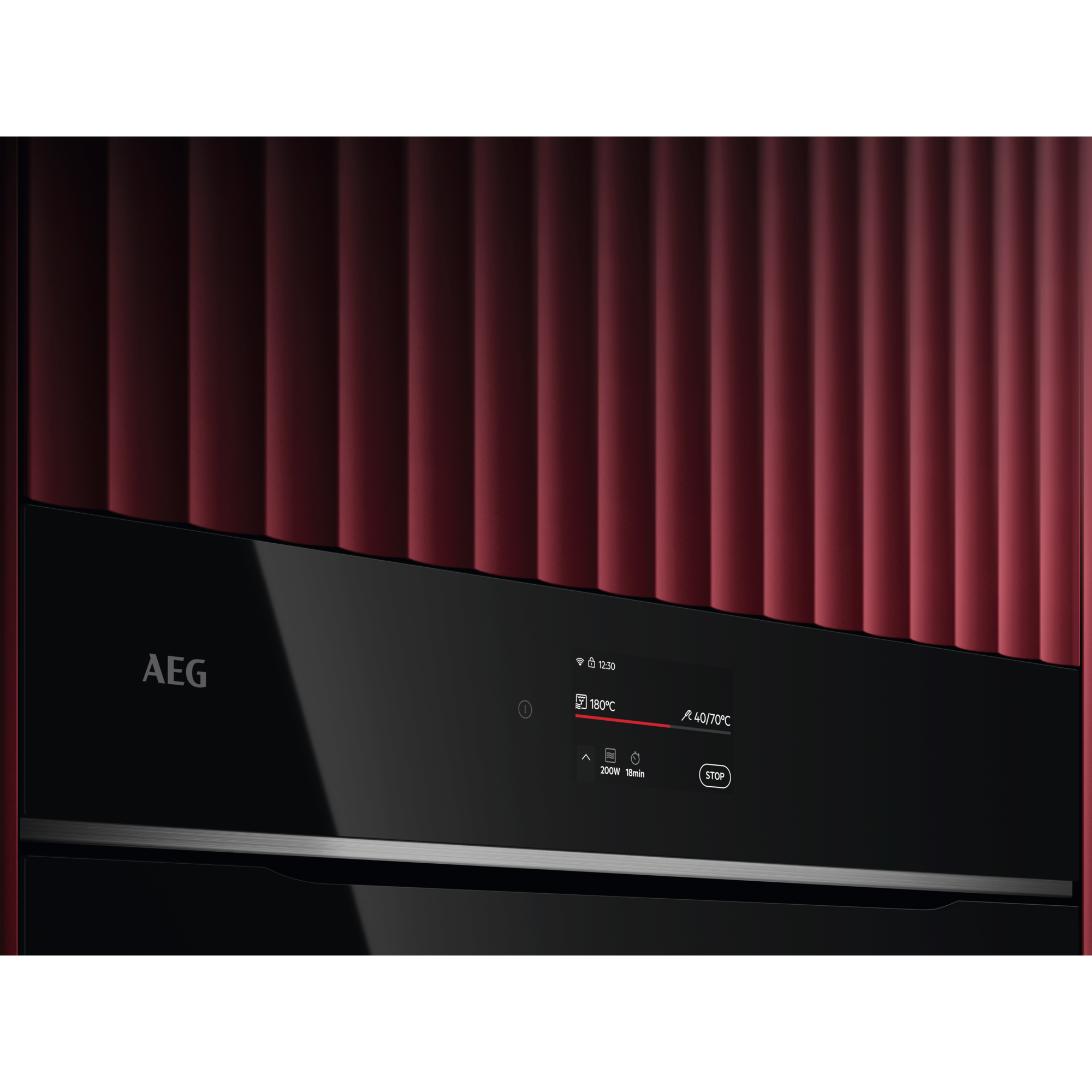 Detalle del horno AEG con una pantalla digital que muestra la temperatura y la hora. Pared texturizada roja detrás.