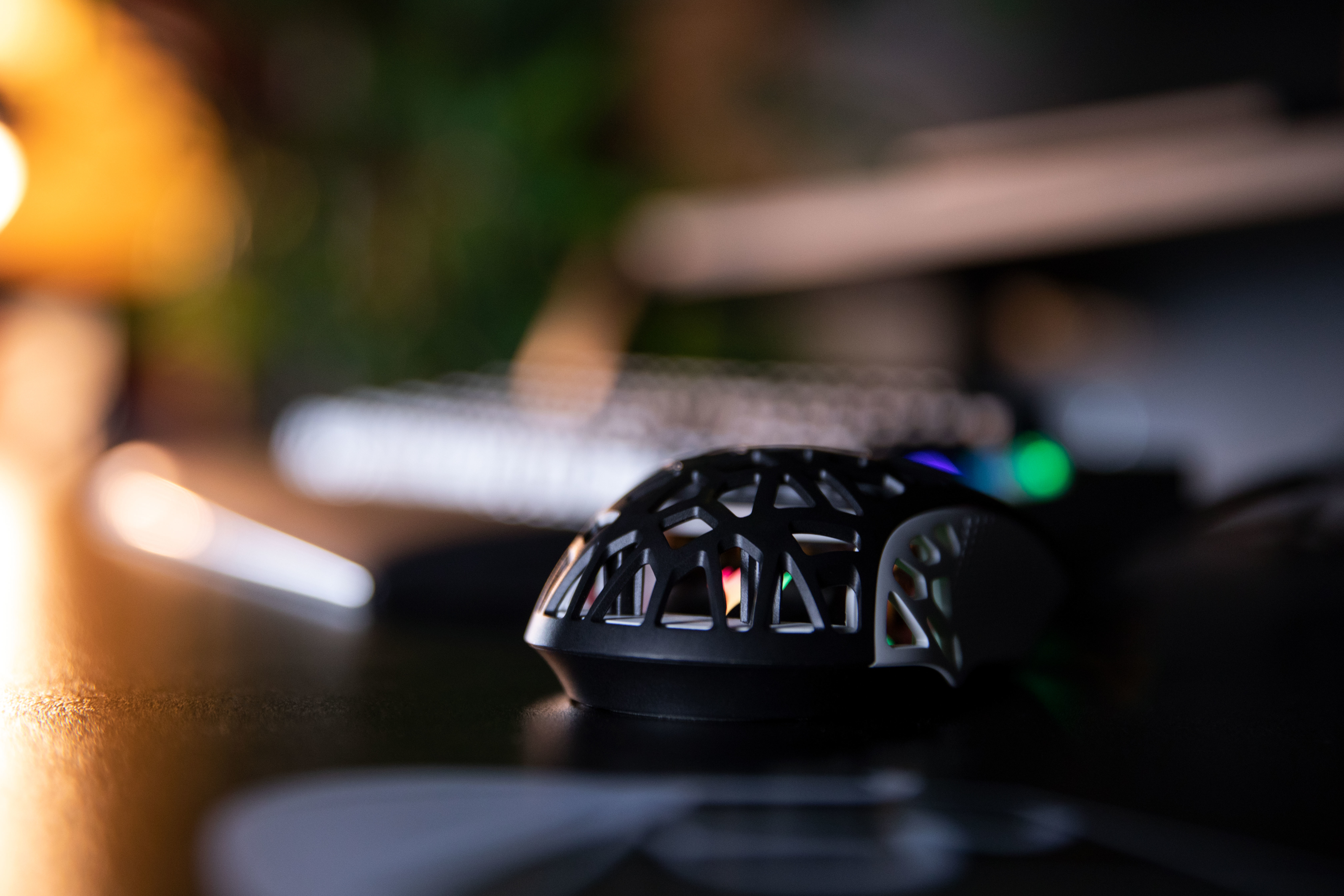 Zbliżenie czarnej myszy na biurku z klawiaturą. Tło jest rozmyte.