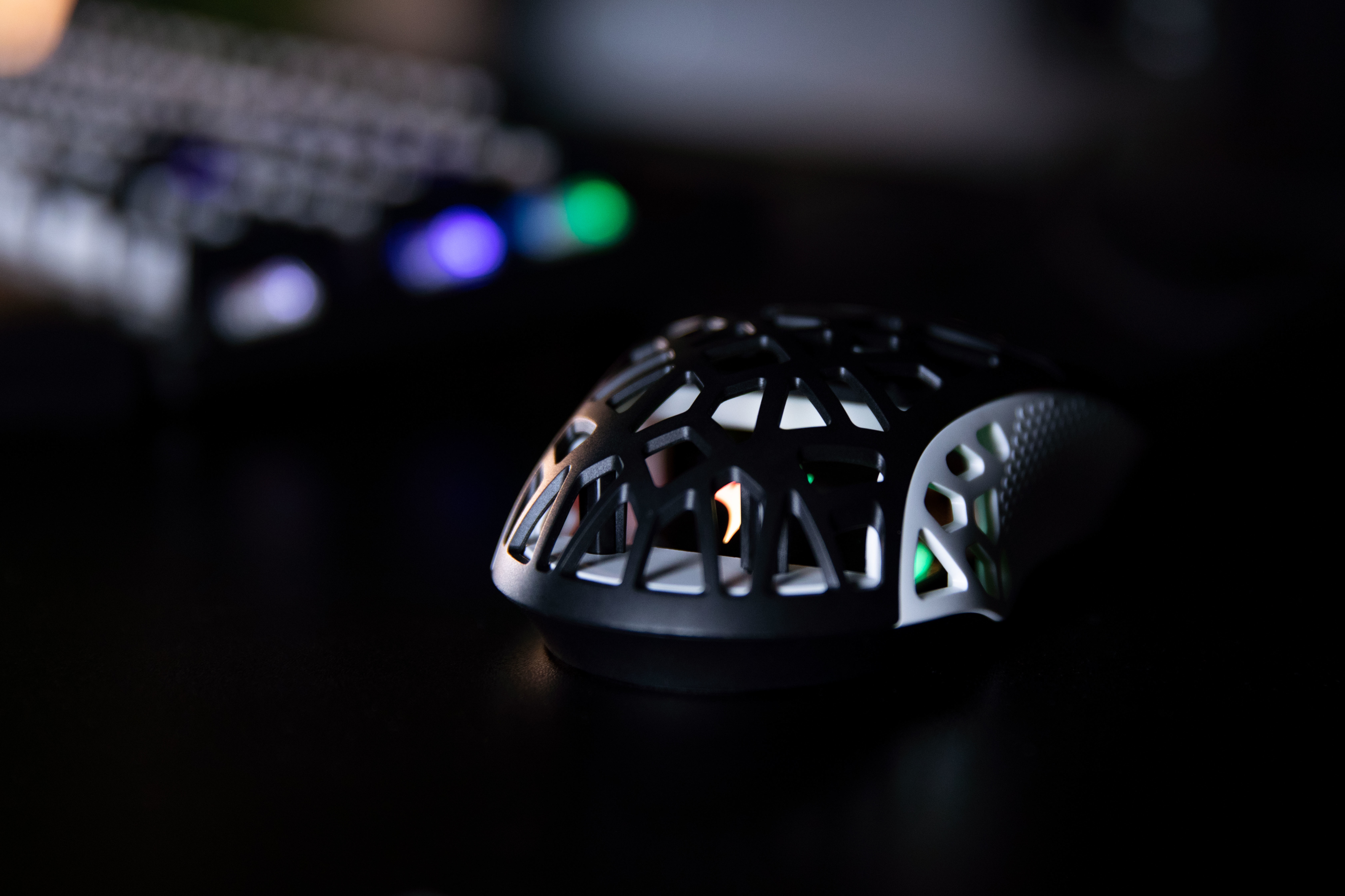 Czarna mysz z wyciętym wzorem, w ciemnym otoczeniu, na czarnej powierzchni.