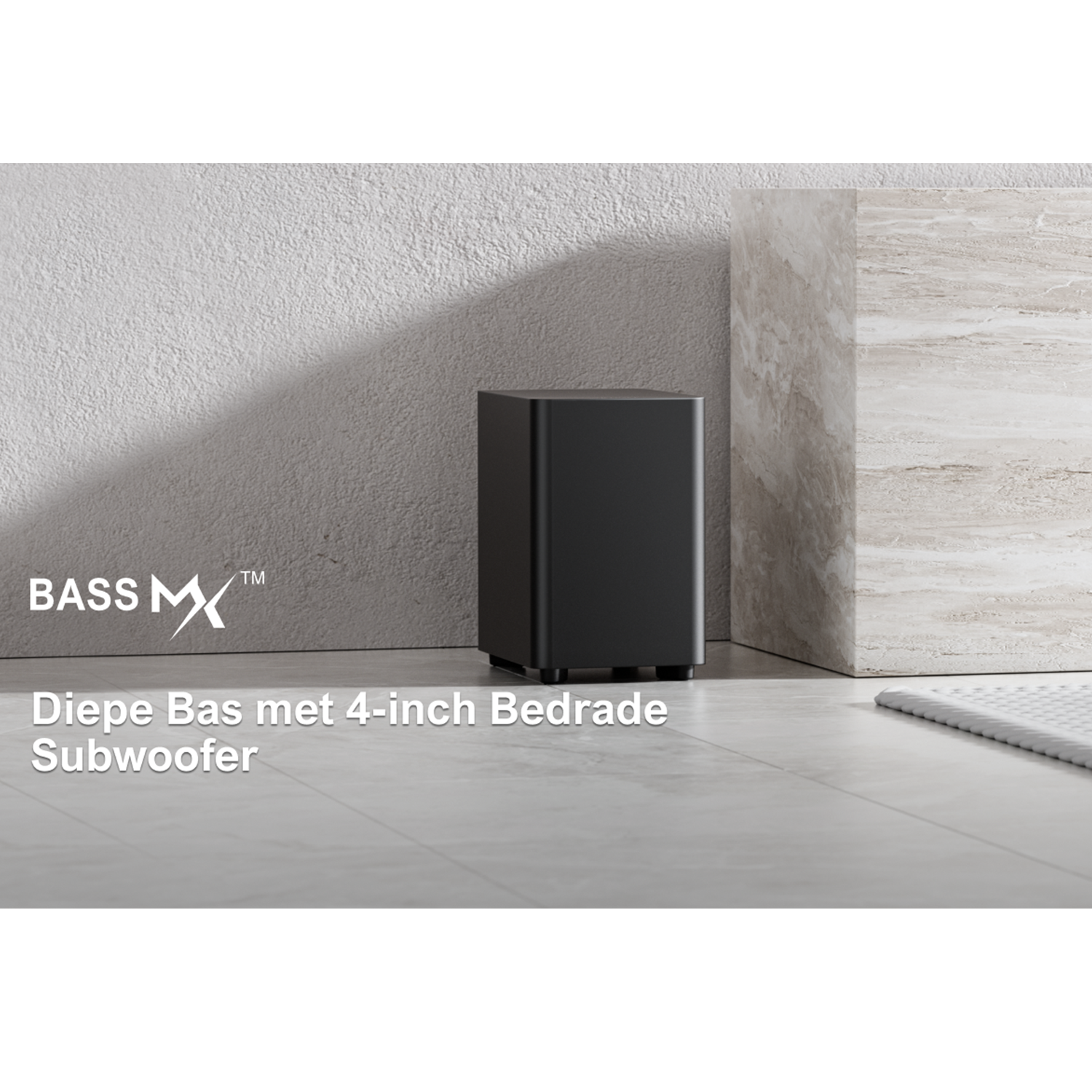 A black subwoofer with a white logo on a gray floor against a white wall.