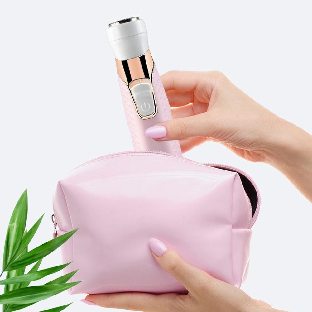 Hand legt rosa Rasierer in rosa Tasche. Grüne Blätter im Hintergrund.