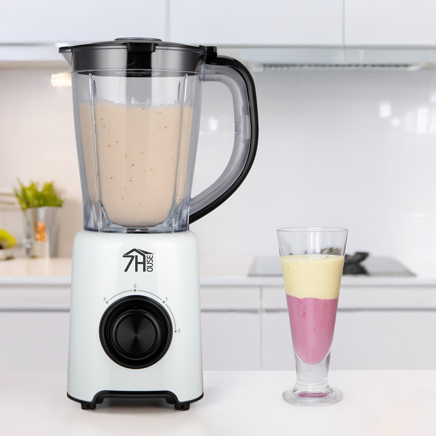 Licuadora blanca con asa negra y vaso de batido. El batido tiene tres capas.