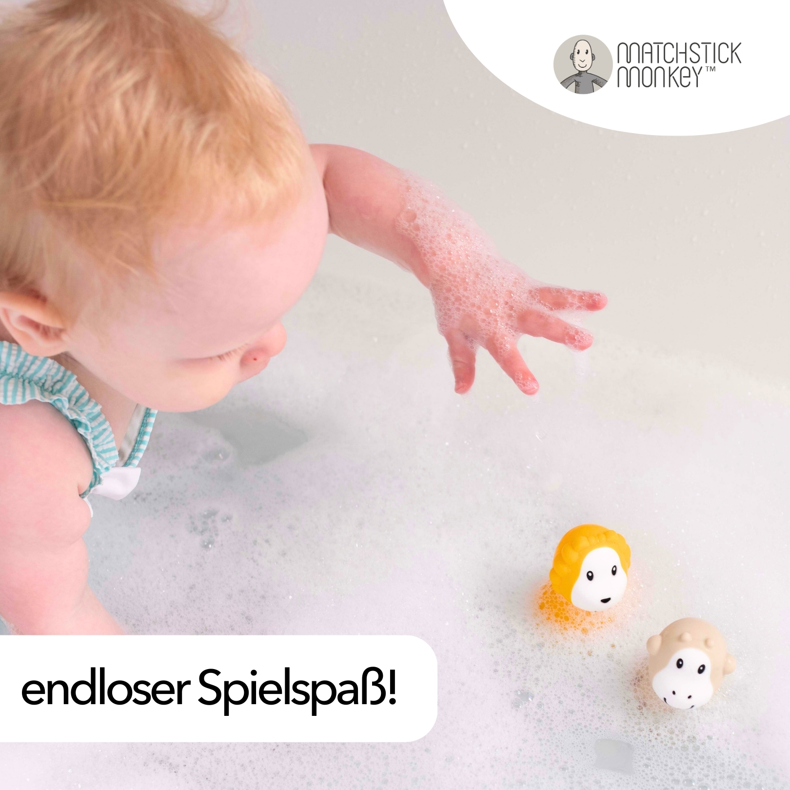 Baby in einer Badewanne, greift nach zwei Badespielzeugen im Wasser.