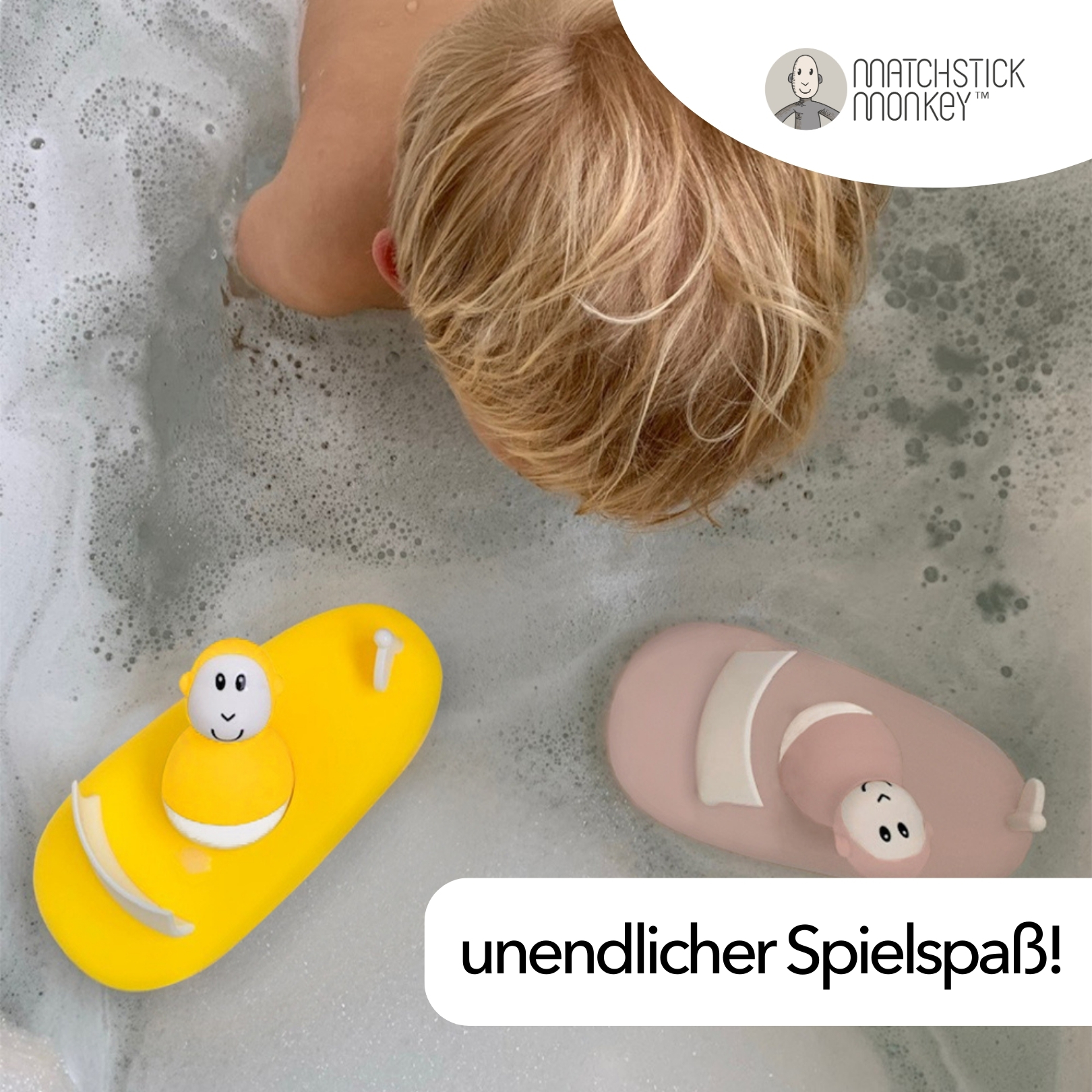 Ein Baby in der Badewanne mit zwei Badespielzeugen. Eines gelb, eines rosa. Das Baby ist blond und schaut nach unten.