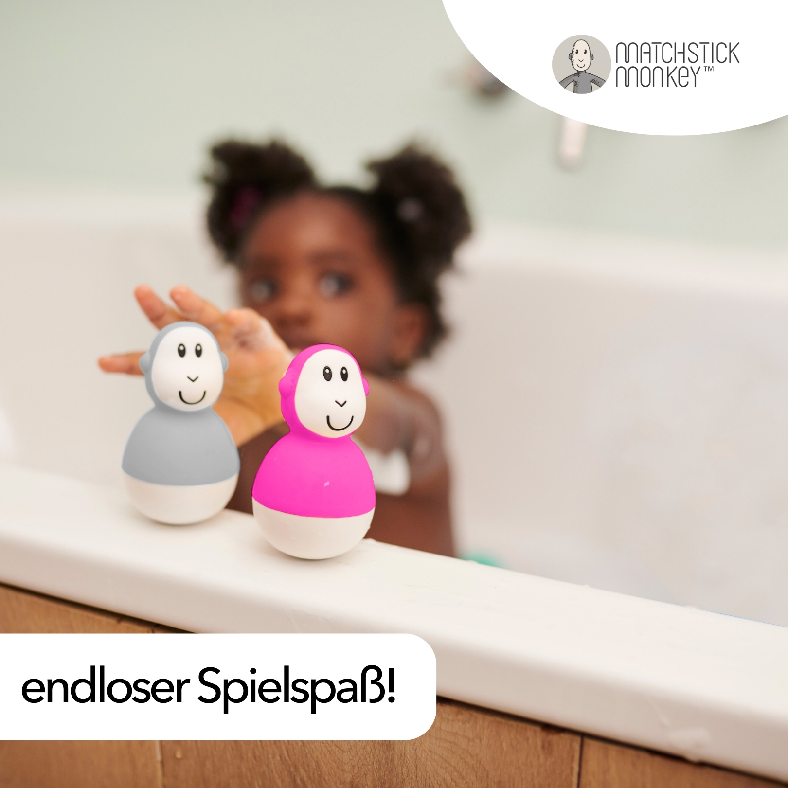 Ein Kind in der Badewanne mit zwei Spielzeugaffen, einer rosa, einer grau.
