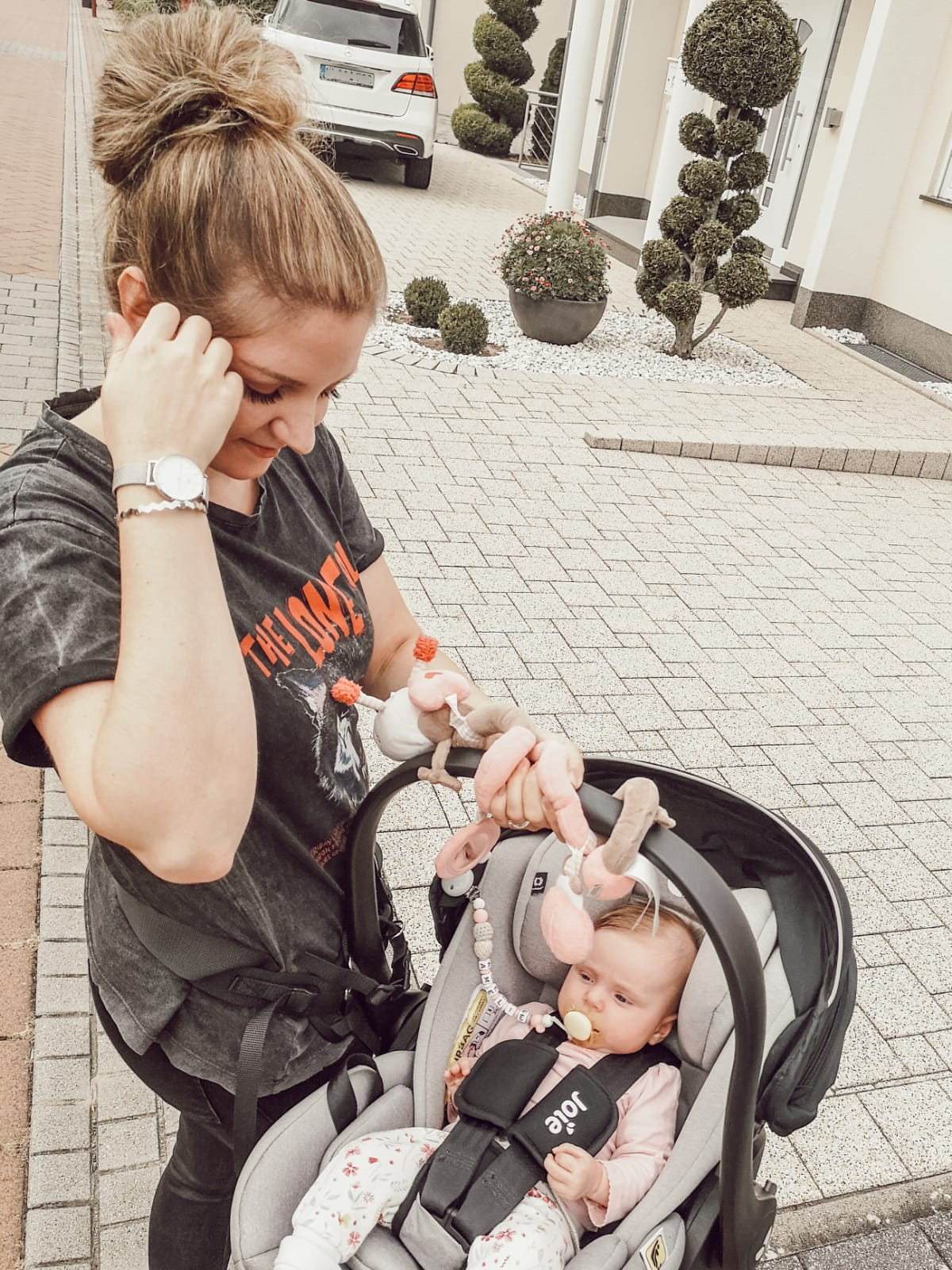 Eine Frau mit Baby im Kinderwagen, schaut nach unten, draußen.