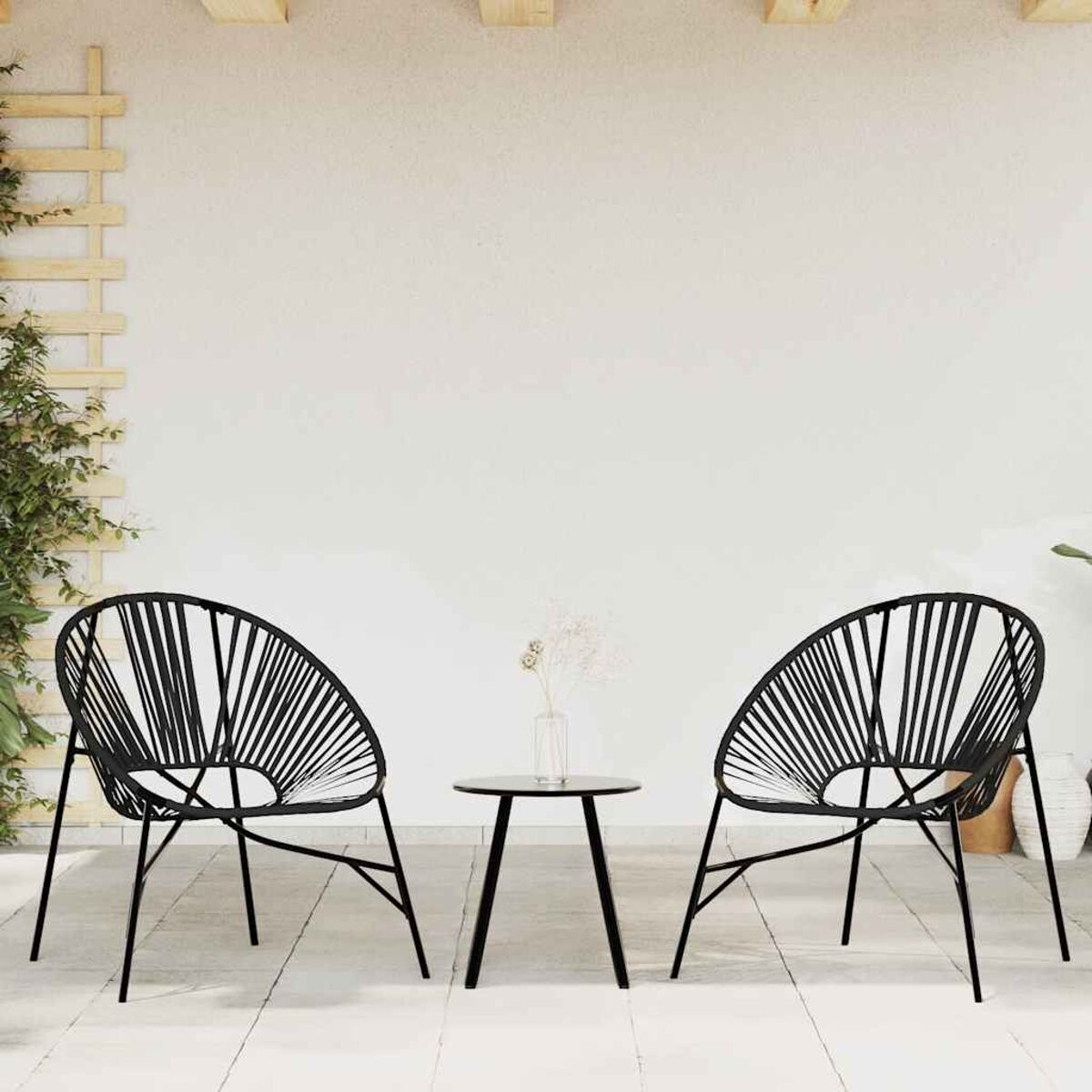 Due sedie nere e un tavolino su un patio con un muro bianco e una pianta rampicante.