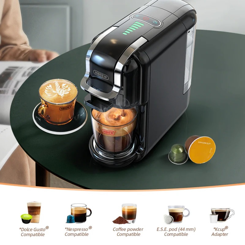 Schwarze Kaffeemaschine mit zwei Kaffeetassen und Kaffeepads darunter, verschiedene Sorten.