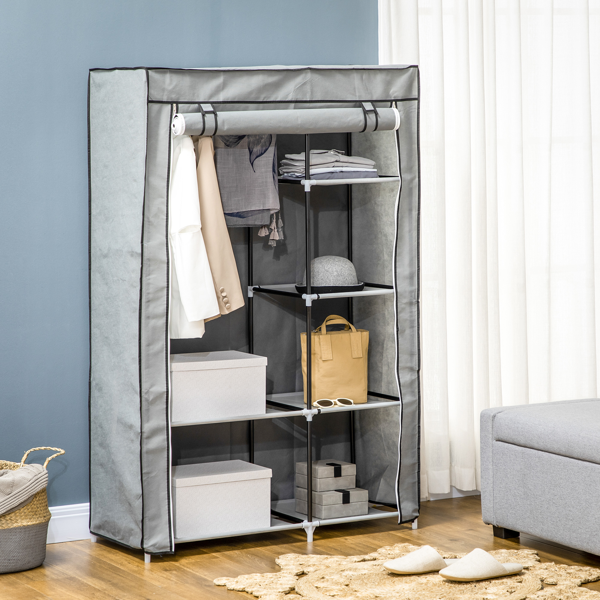Grauer Stoffschrank mit Kleidung, Hüten und Kisten. Hintergrund: blaue Wand und Fenster.