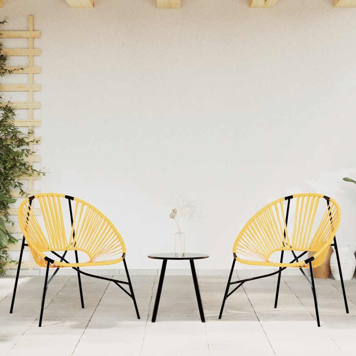 Due sedie gialle e un tavolino nero sono su un patio. Lo sfondo è un muro bianco.