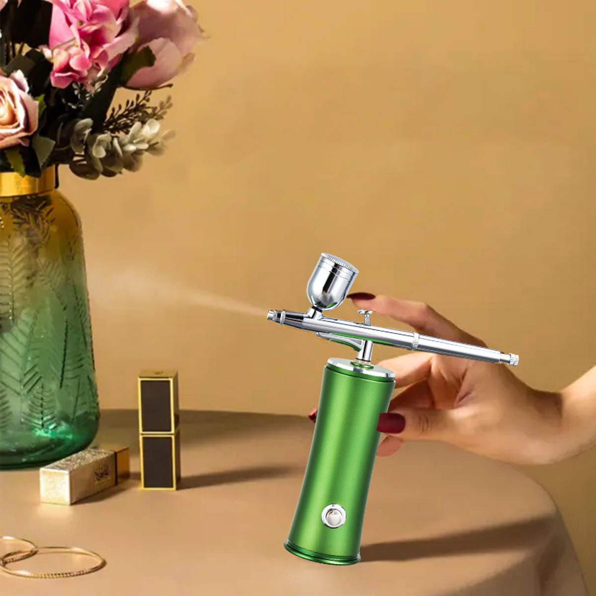 Eine grüne Airbrush sprüht auf einen Tisch mit Blumen und Kosmetika auf beigem Hintergrund.