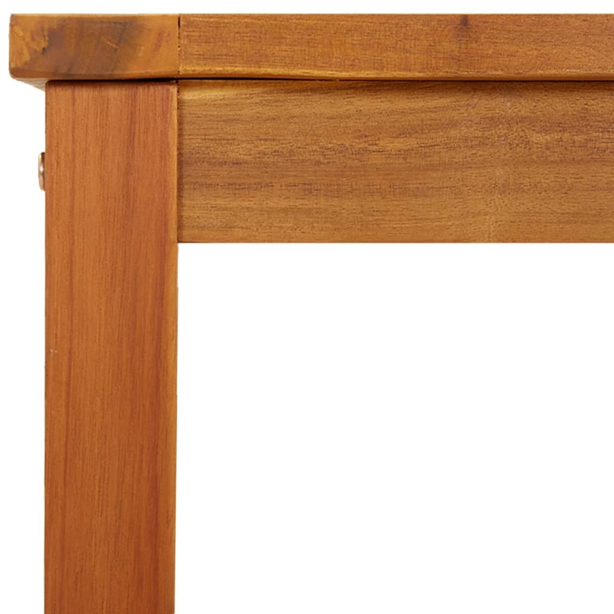 Primo piano di un angolo di tavolo in legno. Il legno è marrone chiaro con venature visibili, che mostra il bordo e una gamba.
