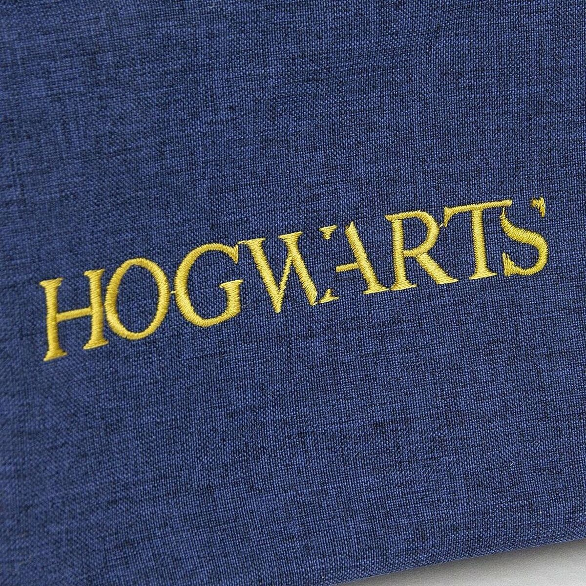 Primer plano de un libro azul oscuro con la palabra 'HOGWARTS' en letras doradas.