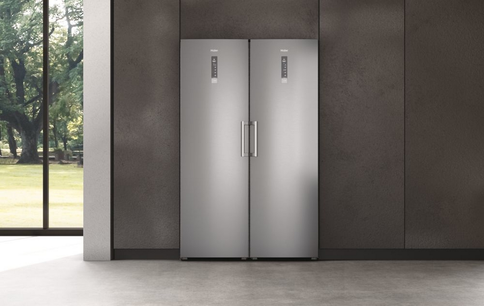 Dos refrigeradores plateados uno junto al otro, logo Haier en cada puerta.