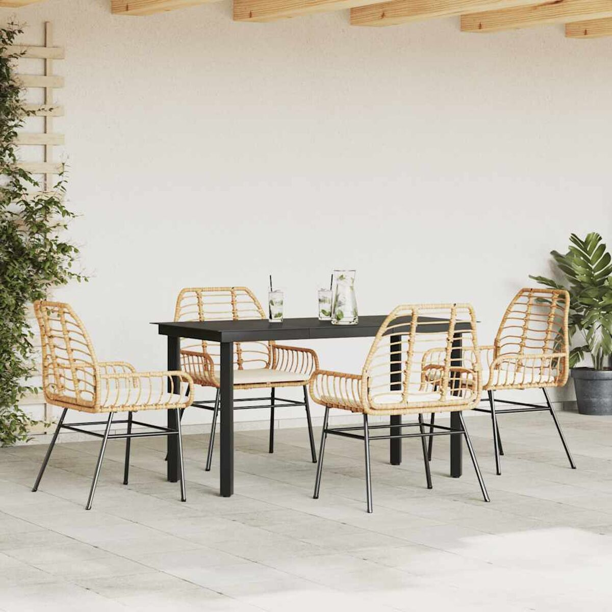 Set da pranzo all'aperto: tavolo nero, quattro sedie. Parete bianca e piante sullo sfondo.