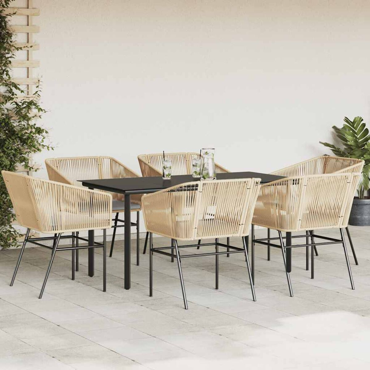 Juego de comedor al aire libre: mesa, seis sillas con asientos de cuerda beige, marcos negros. Fondo: pared blanca, plantas.