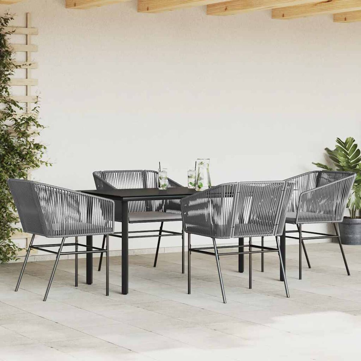 Set da pranzo all'aperto con tavolo nero e sedie grigie, su un patio in legno.
