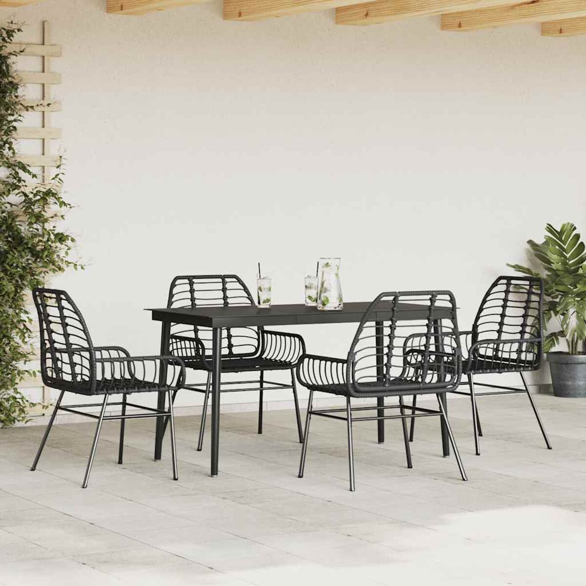 Un set da pranzo all'aperto con un tavolo nero e quattro sedie nere, su un patio con piante.