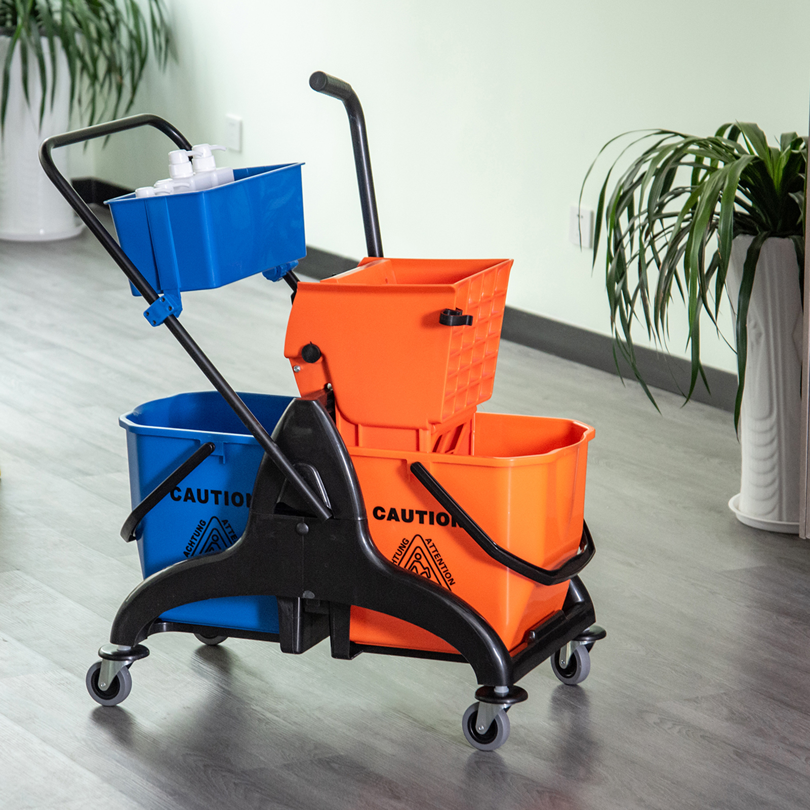 Reinigungswagen mit blauen und orangefarbenen Eimern, drinnen mit Pflanzen.
