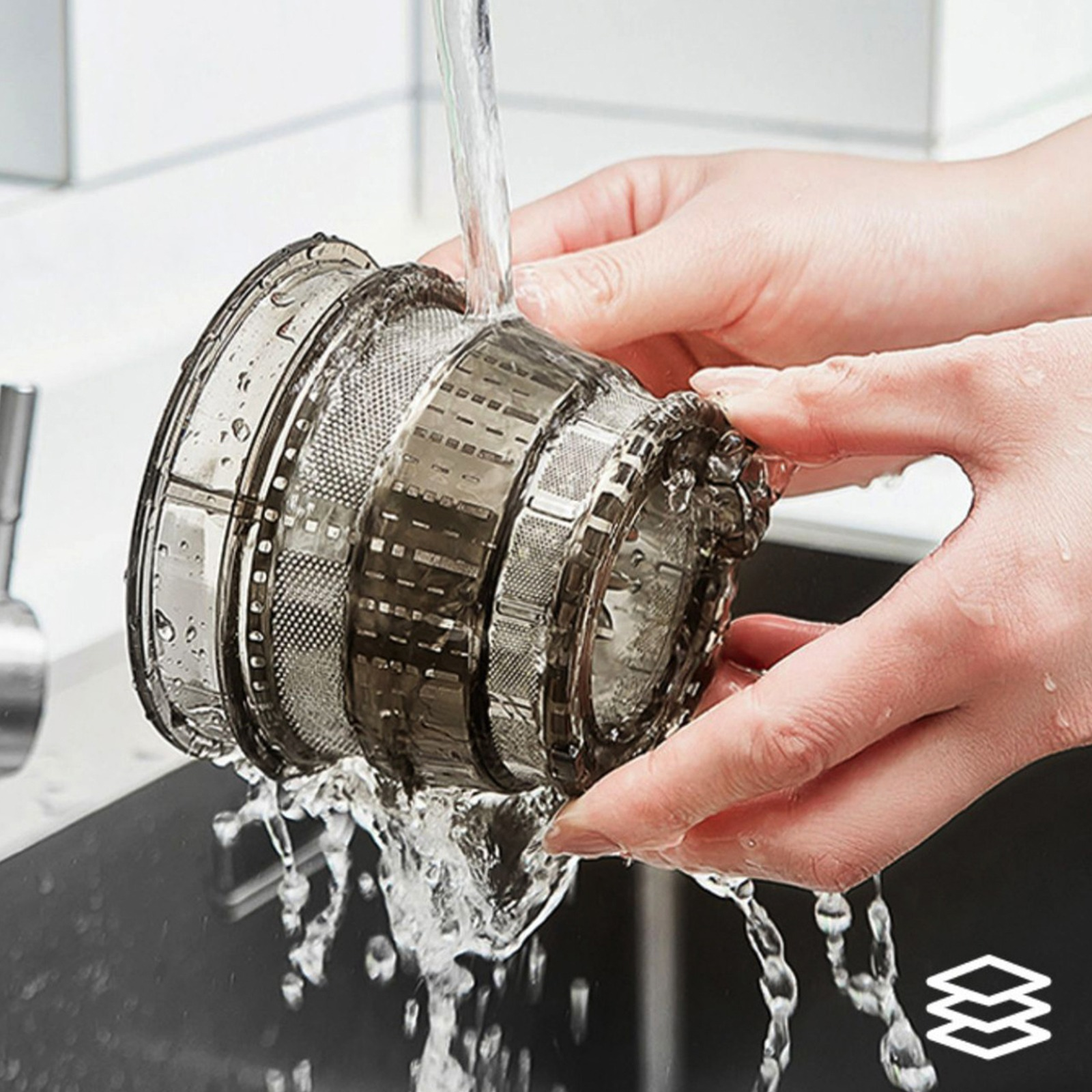 Hände waschen einen dunkelgrauen Saftfilter unter fließendem Wasser. Klare Tröpfchen sind sichtbar.