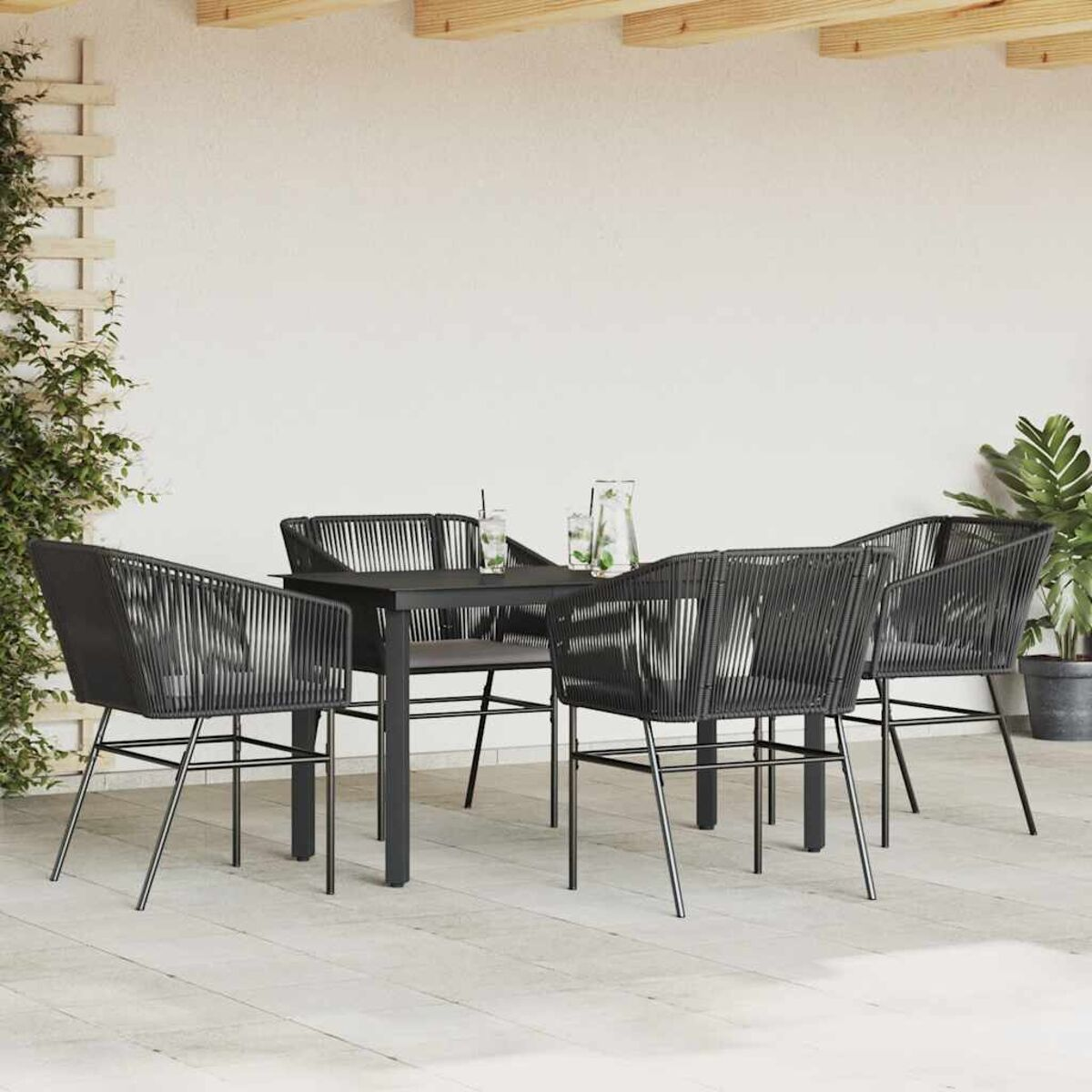 Arredamento per patio esterno con tavolo e sedie neri. Include piante, bevande e uno sfondo dai toni neutri.