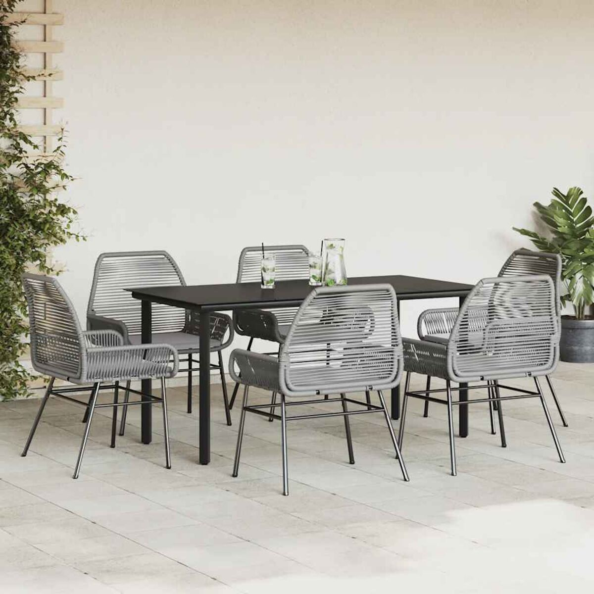 Essgruppe im Freien mit schwarzem Tisch und grauen Stühlen. Eine Terrasse mit Pflanzen.