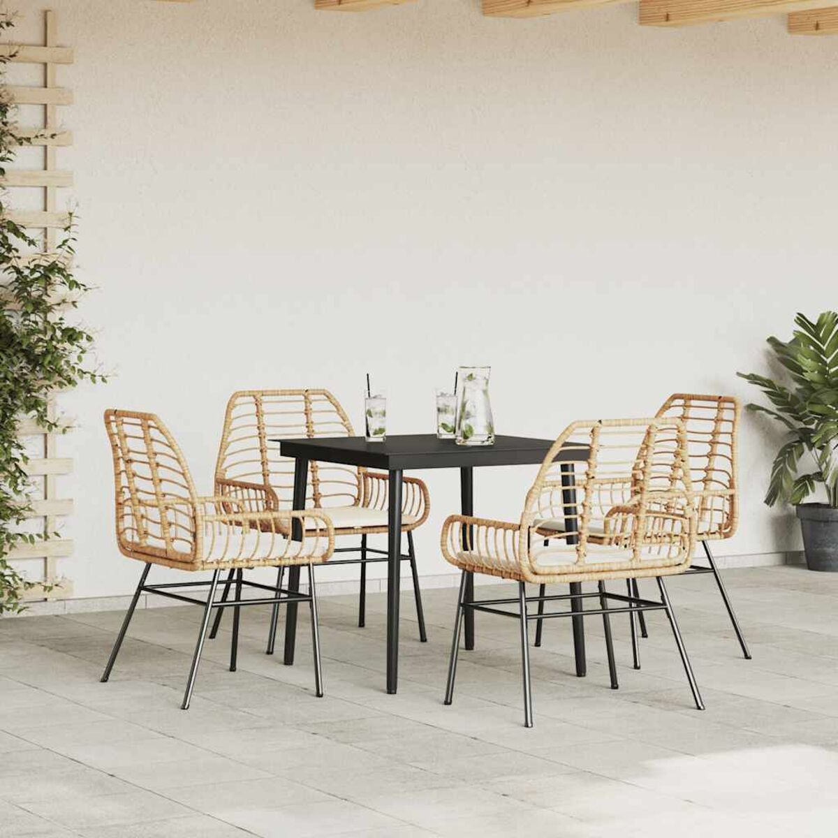 Un set da pranzo all'aperto con un tavolo nero, quattro sedie intrecciate e una pianta.