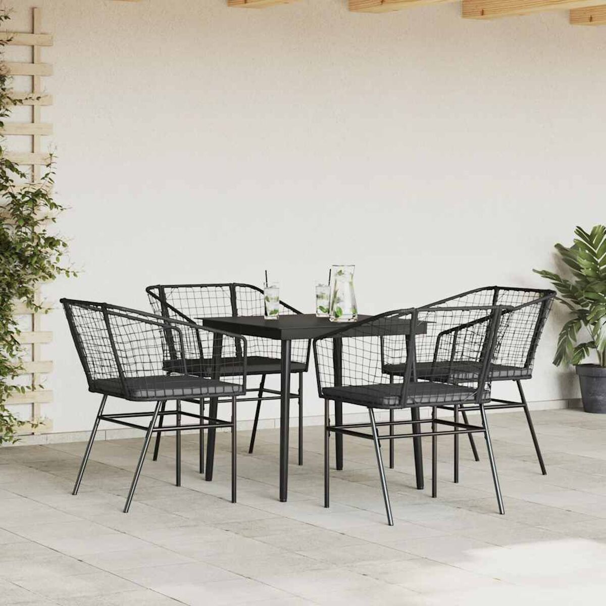 Juego de muebles de exterior. Mesa cuadrada con marco de metal negro y cuatro sillas. Pared blanca y suelo claro.