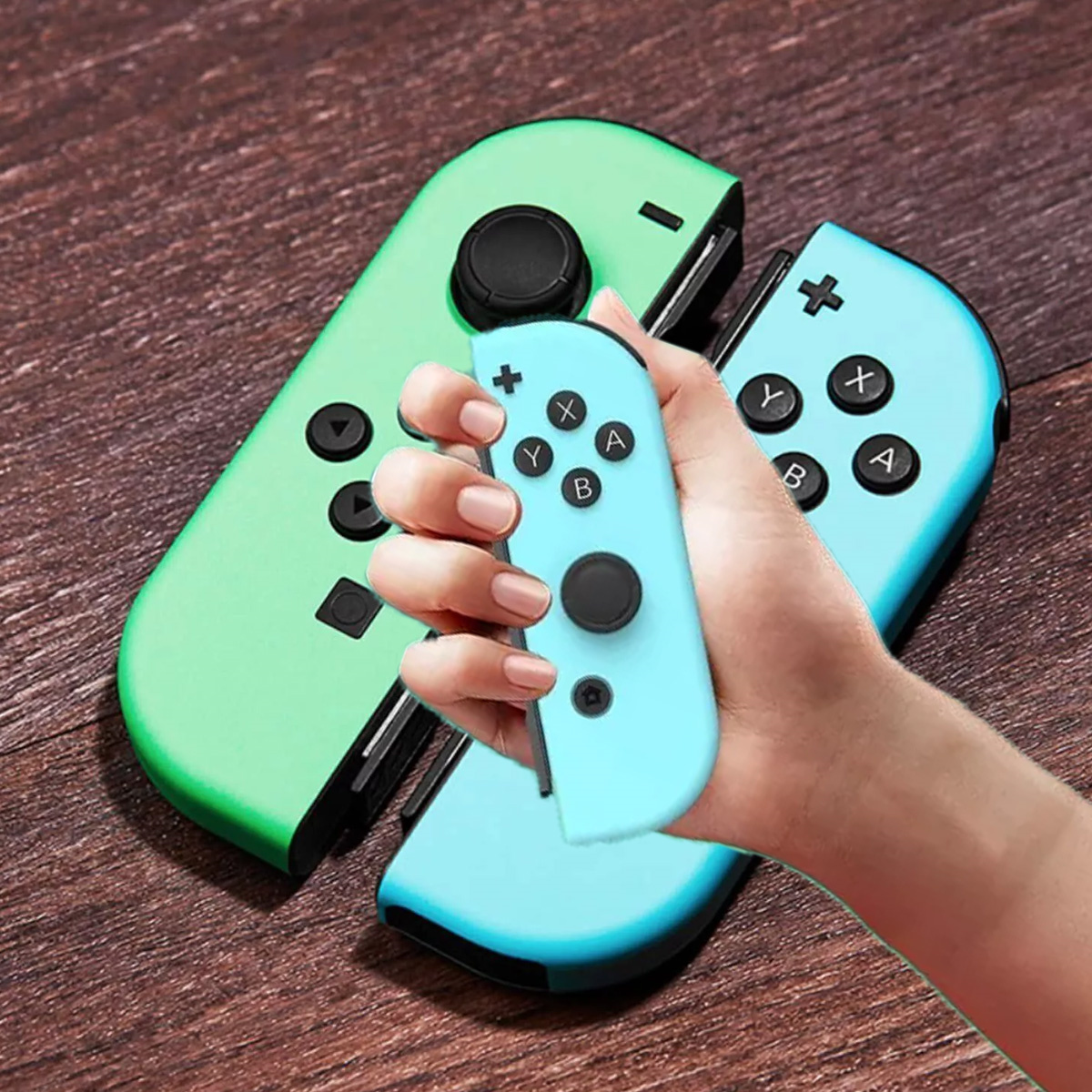 Eine Hand, die zwei bunte Joy-Con-Controller hält, einer grün und einer blau.