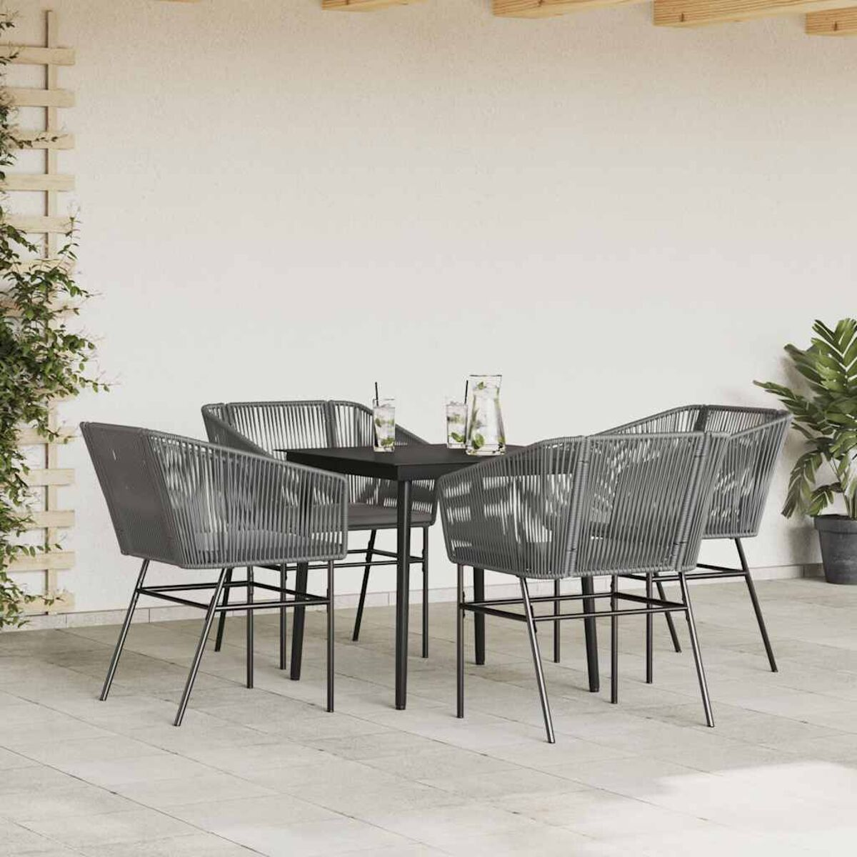 Essgruppe im Freien mit vier grauen Seilstühlen und einem schwarzen Tisch vor einer weißen Wand.