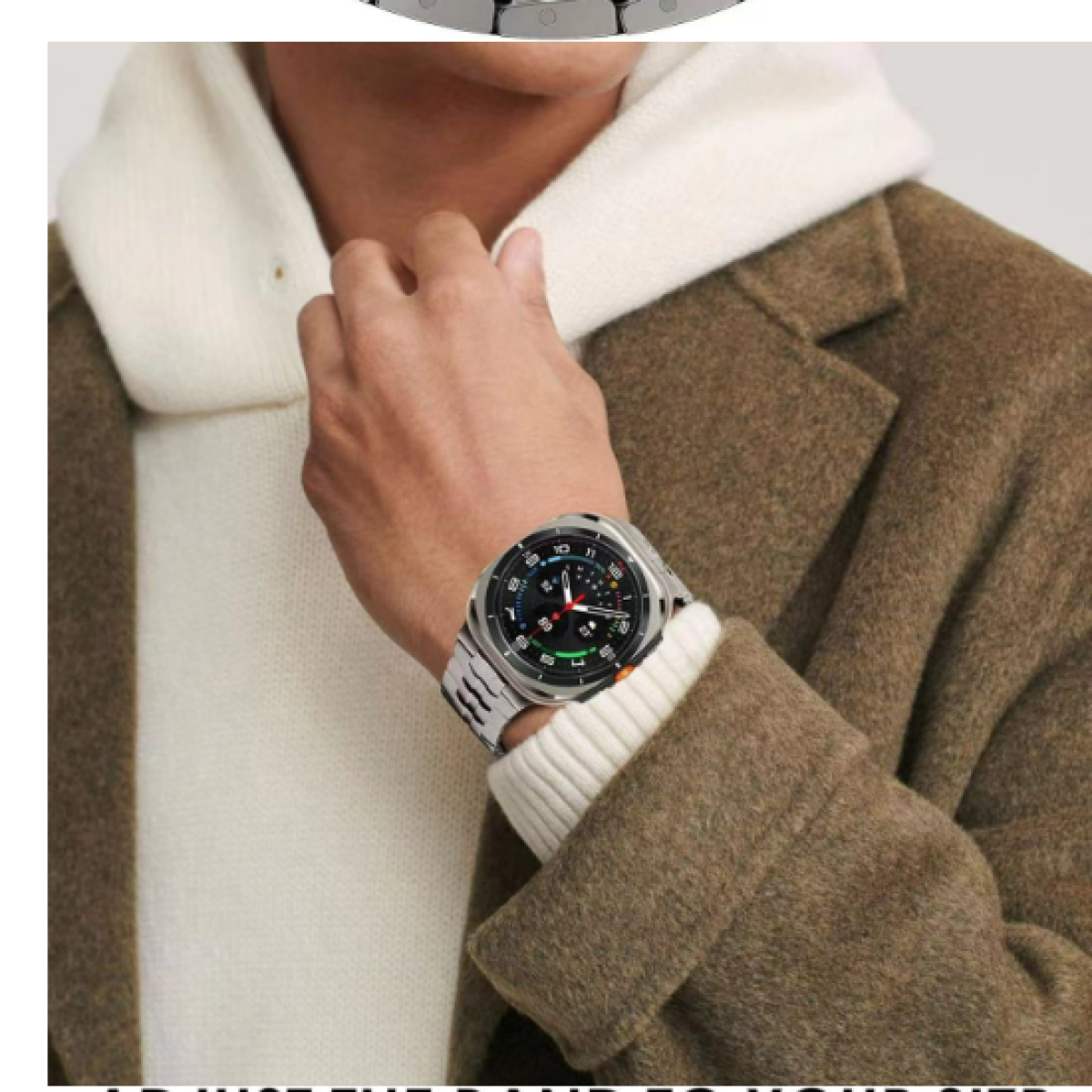 Polso di un uomo con orologio nero e argento, indossa un maglione bianco e un cappotto marrone.
