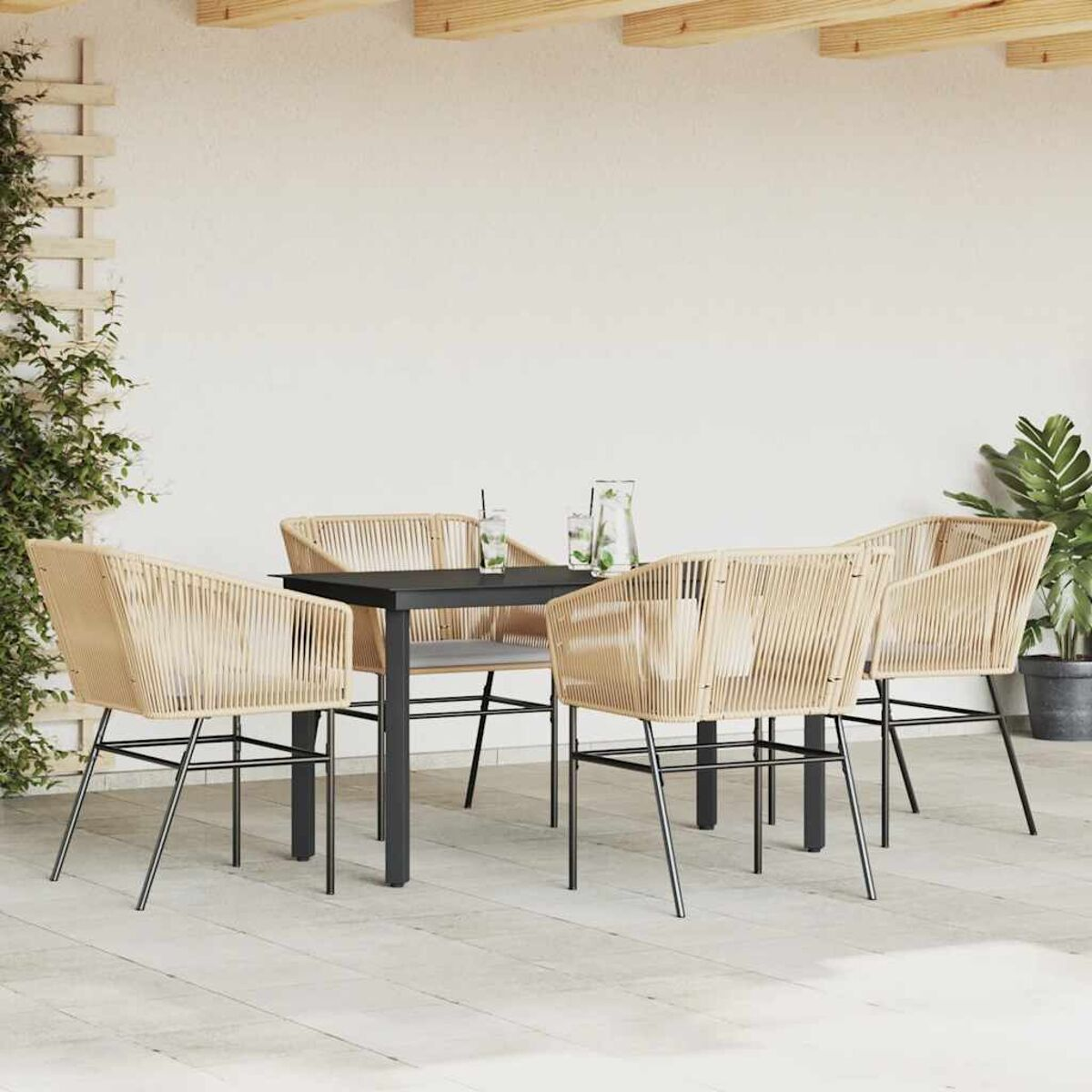 Set da pranzo da esterno con tavolo nero e quattro sedie in vimini, su un patio.