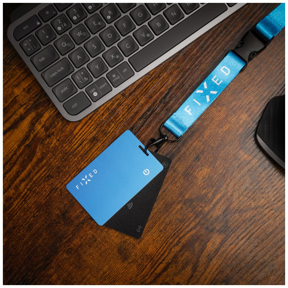 Schreibtisch-Setup: Tastatur, blaue Karte mit Logo, schwarze Karte, Lanyard mit Text und Maus.